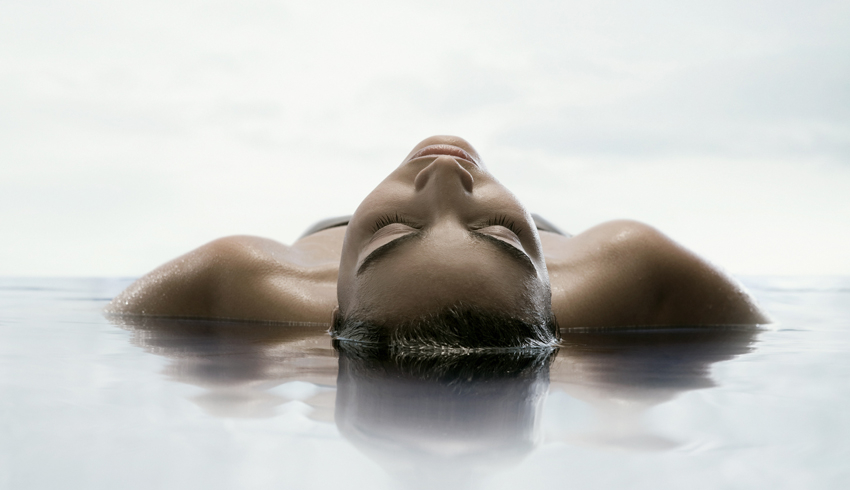 A woman floats in water in a spa pool